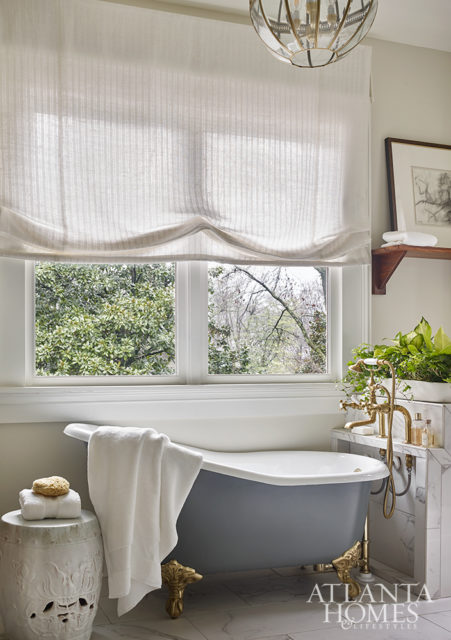 A claw-foot soaker tub with brass hardware from Waterworks leans into the home’s historic character. The light fixture is from Circa Lighting.