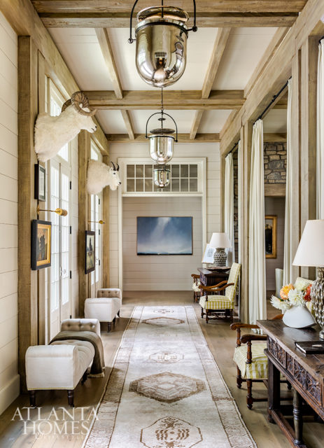 A 28-foot-long Oushak rug and linen sheers dress up the entry foyer, which is illuminated by large bell jar lanterns from The Urban Electric Co.