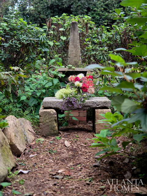 A granite bench and antique obelisk make a striking focal point.