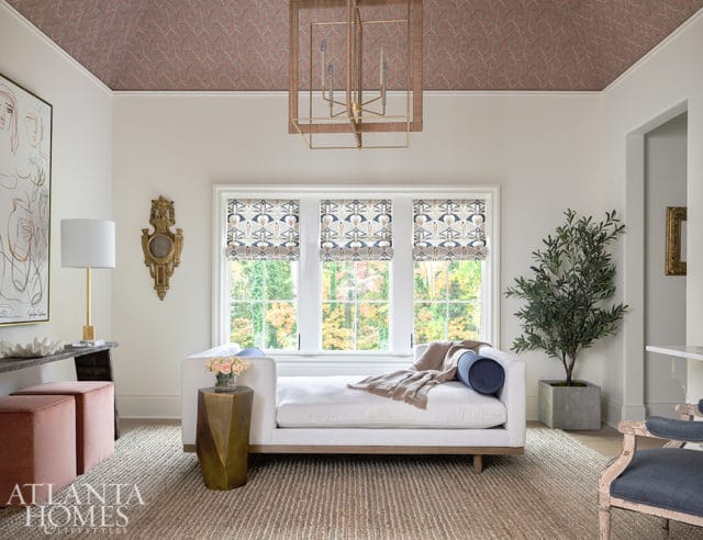 Living room with pink patterned wallpaper on the ceiling, a white chaise lounge, and a large abstract painting.