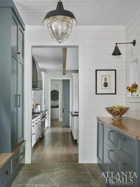 Hallway with shiplap walls, gray cabinetry, wood countertops, and a view into a kitchen with stainless steel appliances and white cabinetry.