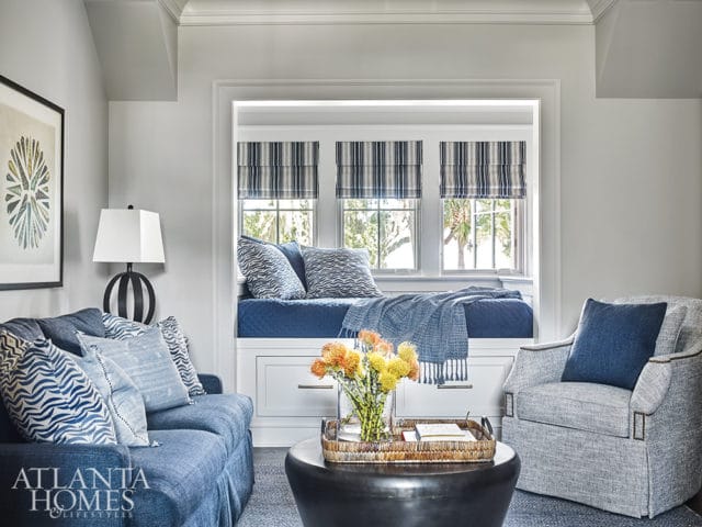 Living room with blue sofa, gray armchair, and built-in window seat with blue and white striped shades.