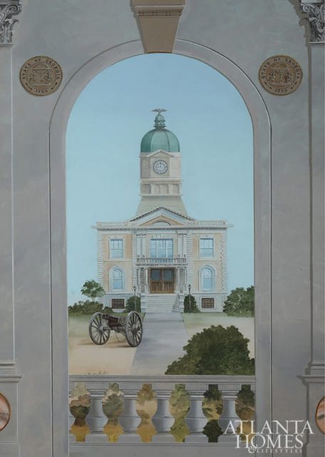Mural depicting a classical building with a dome and clock tower, a cannon in the foreground, and seals of the State of Georgia on either side of an archway.