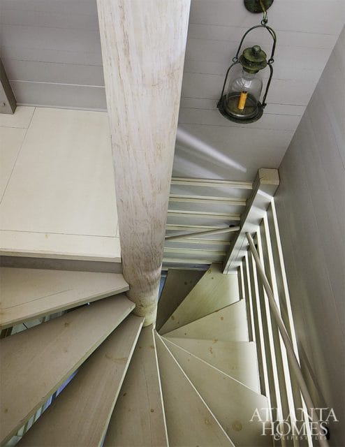Light wood spiral staircase with a central wooden column and a vintage lantern hanging from the ceiling.