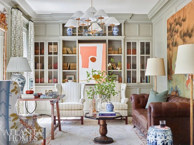 Living room with built-in bookshelves, two striped wingback chairs, a leather sofa, and abstract art.