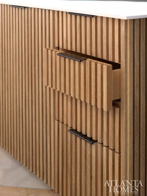 Close-up of a wooden cabinet with vertical slats and black drawer pulls. One drawer is slightly open.