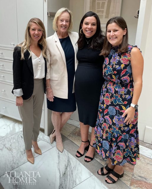 Four women pose for a photo in front of a wall of drawers and marble flooring. The Atlanta Homes & Lifestyles logo is visible in the bottom left corner.