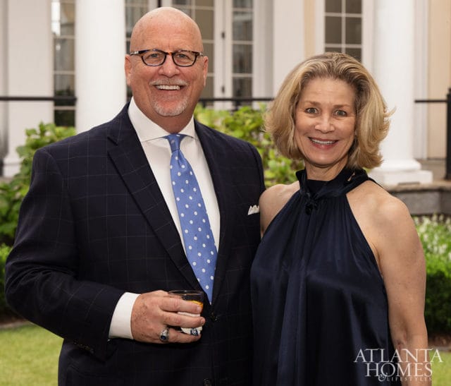 Man in suit holding drink, woman in navy dress, Atlanta Homes & Lifestyles logo