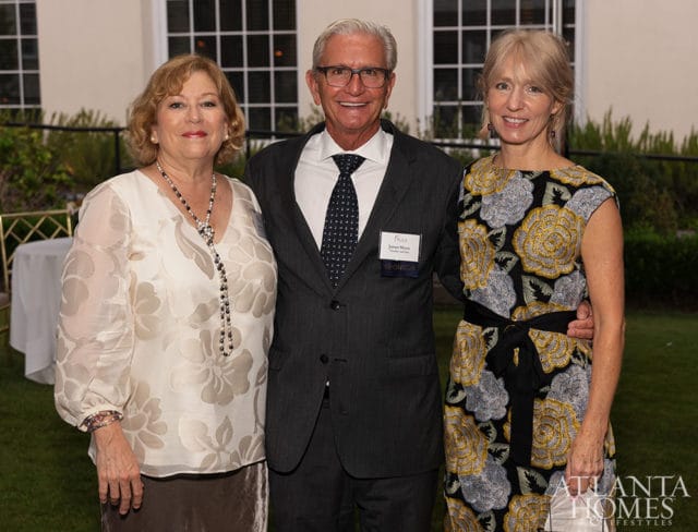 Three people posing outdoors with a building in the background. Atlanta Homes & Lifestyles logo