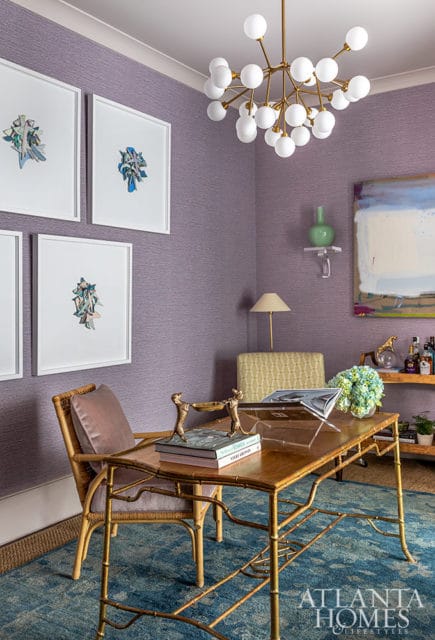 Purple textured wallpaper office with gold bamboo desk, rattan chairs, and abstract art.