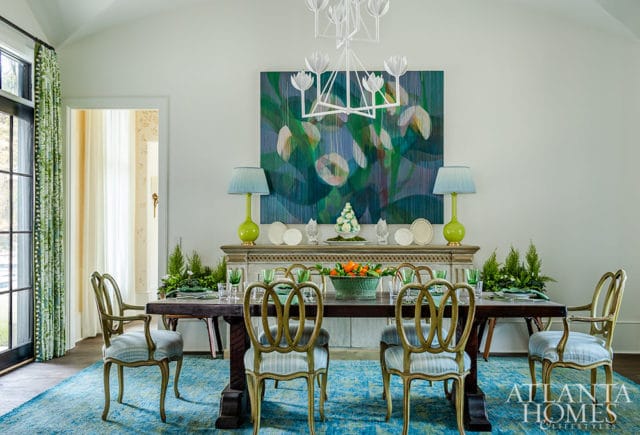 Dining room with dark wood table, blue rug, abstract art, and green curtains.