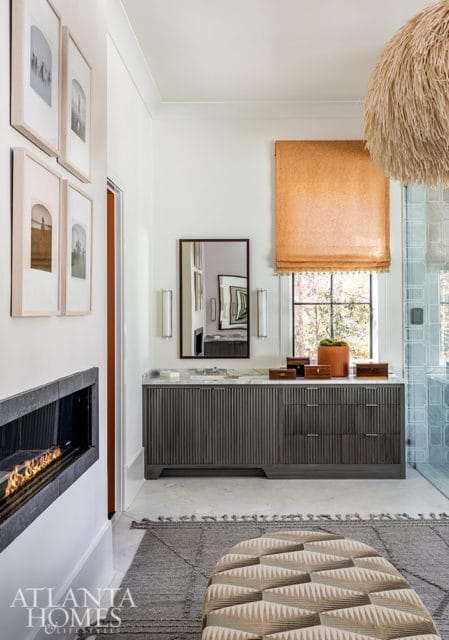 Modern bathroom with a linear fireplace, fluted gray vanity, marble countertop, and large textured