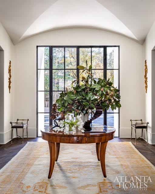 Foyer with arched ceiling, round wooden table, floral arrangement, and Atlanta Homes & Lifestyles