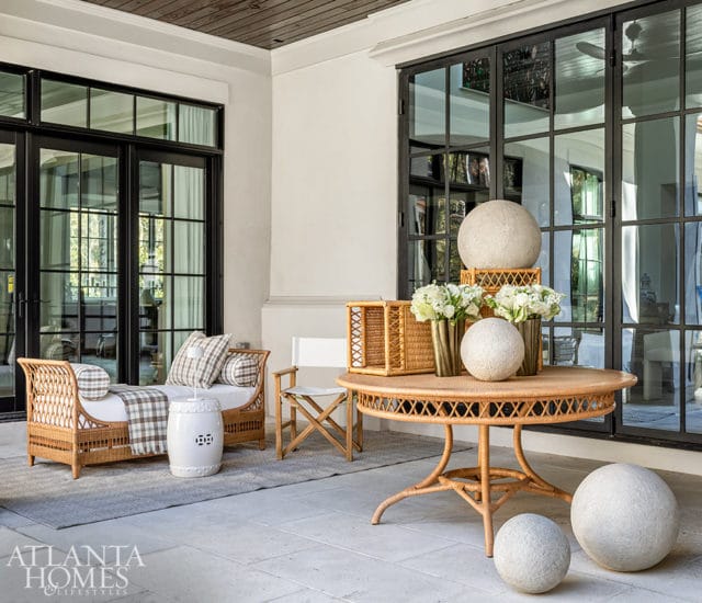 Wicker daybed with plaid cushions and white ceramic stool on rug