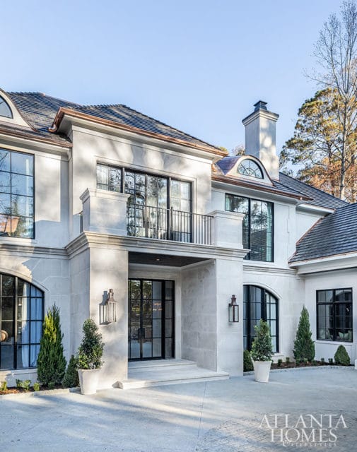 Modern stone house with black-framed windows and a covered entryway.