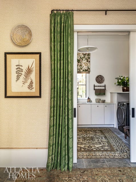 Laundry room with white cabinets, gray stone floor, and patterned green curtains.