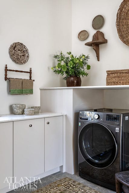 Laundry room with gray LG washer, white cabinets, and decorative wall hangings.