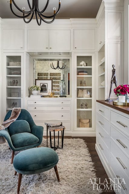 White closet with glass doors, teal armchair, ottoman, and shag rug.