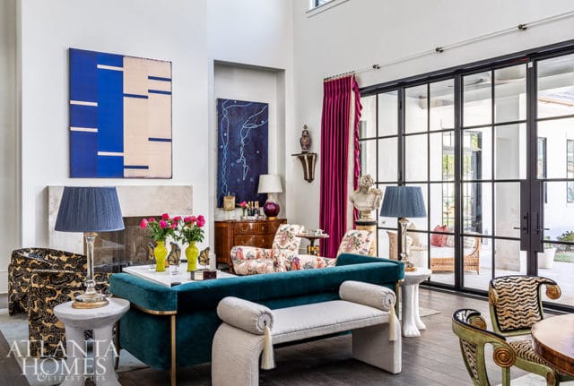 Living room with teal sofa, patterned chairs, abstract art, and large glass doors