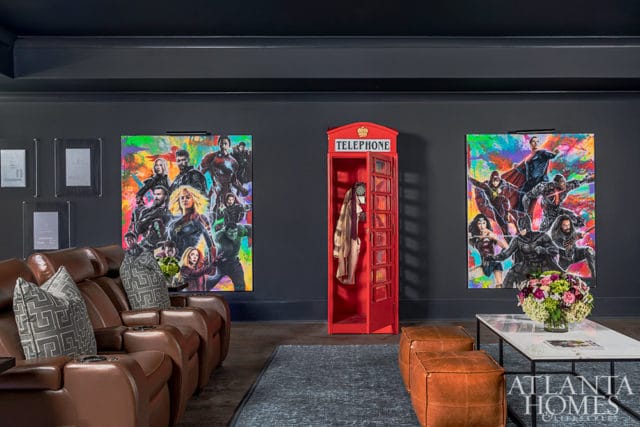 Dark gray room with leather recliners, superhero art, and a red telephone booth