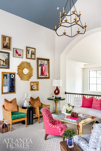 Living room with blue ceiling, gallery wall, rattan chairs, and pink striped armchair.