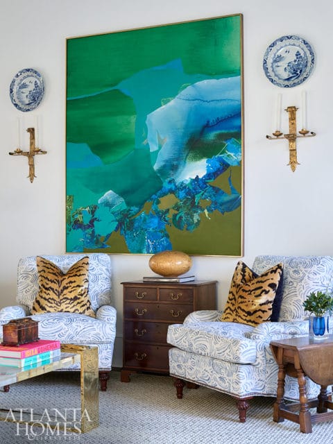 Living room with abstract green and blue art, patterned armchairs, and antique chest