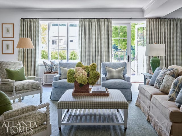 Living room with blue chairs, sofa, and plaid ottoman. Green hydrangeas in basket.
