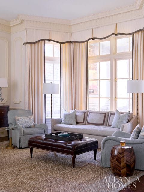 Living room with light gray sofa, armchairs, leather ottoman, and patterned rug.