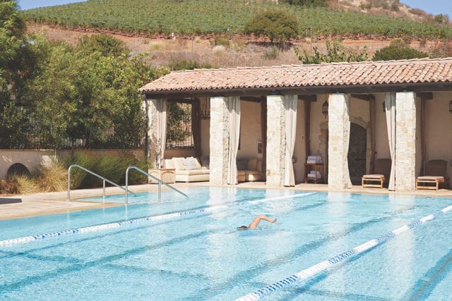 Swimming pool with lap lanes and a covered cabana with stone columns and seating.