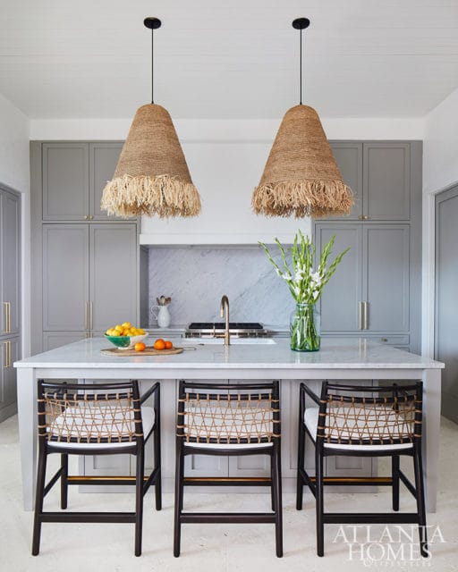 Gray kitchen with island, woven bar stools, and large jute pendant lights.