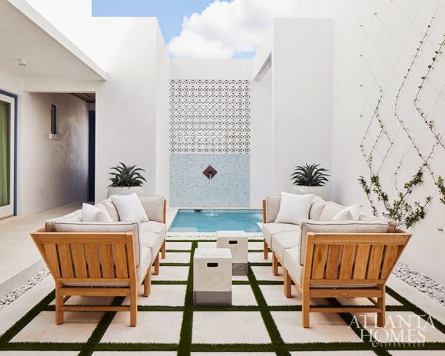 Courtyard with two teak sofas, a small pool, and a patterned tile wall.