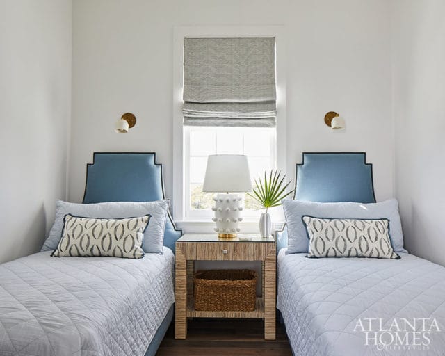Bedroom with two twin beds, blue upholstered headboards, and patterned accent pillows.