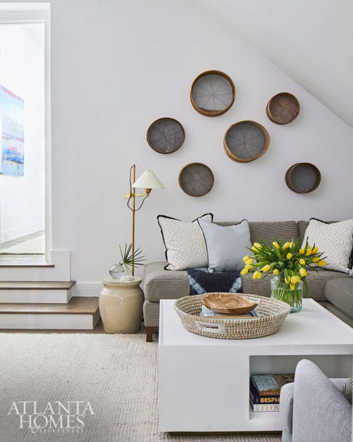 Living room with gray sofa, white coffee table, and wall decor of vintage sieves.