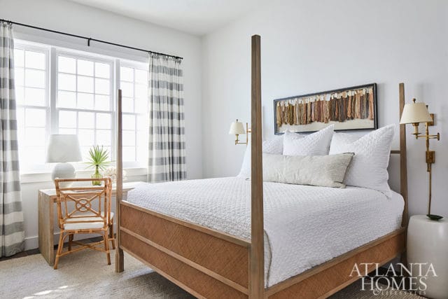 Bedroom with white bedding, a wooden four-poster bed with woven sides, and a desk with a rattan