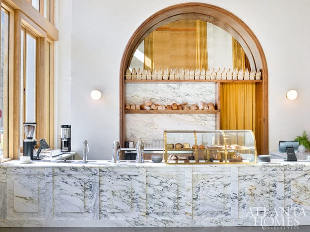 Marble counter with coffee machines, pastry display case, and shelves of bread.