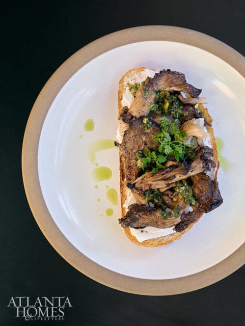 Toasted bread with creamy spread, topped with sautéed mushrooms and herbs.