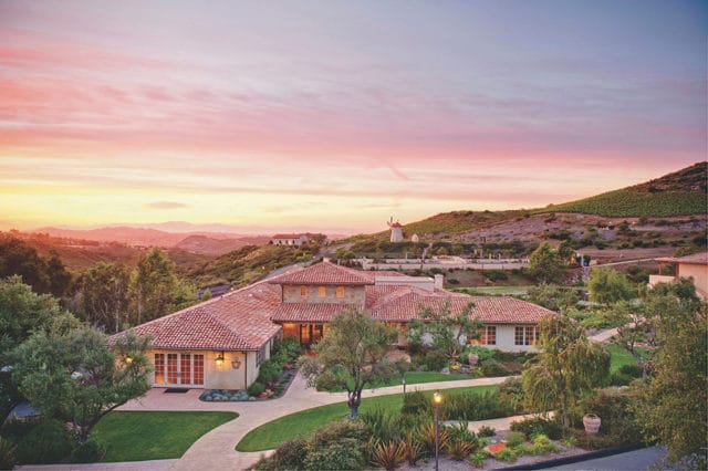 Large house with red tile roof and stucco exterior at sunset