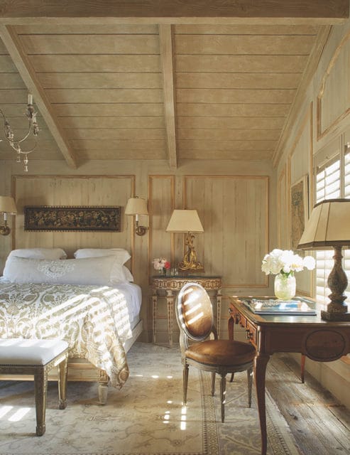 Bedroom with paneled walls, beamed ceiling, and ornate furniture.