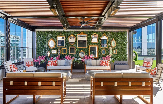 Rooftop terrace with green wall, ornate mirrors, sofas, chairs, and wooden pergola