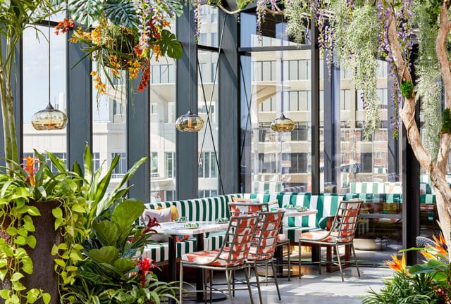 Restaurant dining area with green and white striped booths, patterned chairs, and abundant hanging