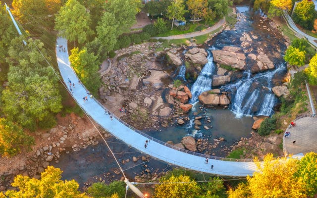 Liberty Bridge suspension bridge over waterfalls and rocky riverbed with trees