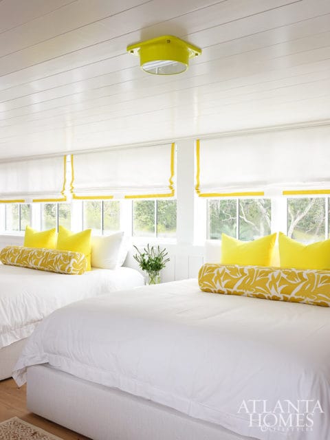 Bedroom with two white beds, yellow pillows, and a yellow ceiling light