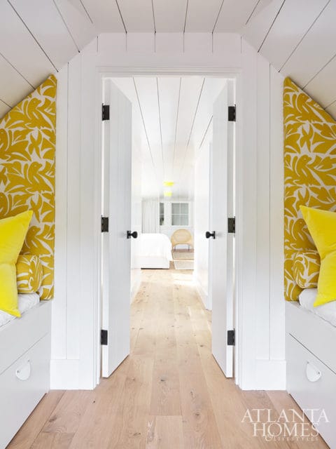 Hallway with white paneled walls and ceiling, yellow patterned accent walls, and built-in white