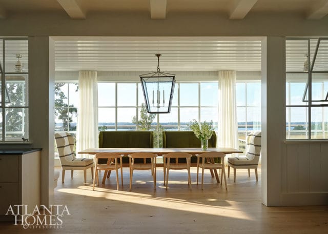 Dining room with light wood table, chairs, and striped wingback chairs. Green banquette seating.