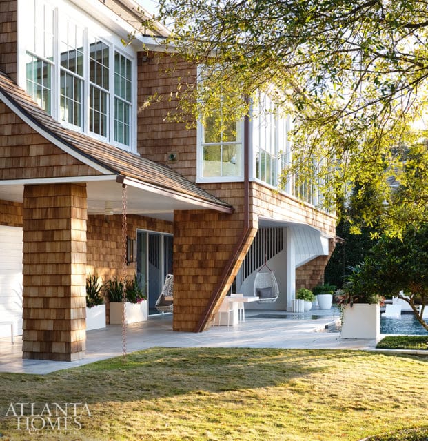 Cedar shake house with large windows, covered porch, and outdoor seating area.