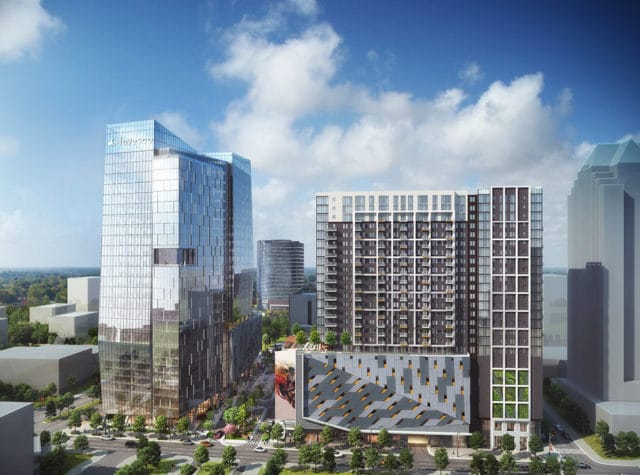 Glass skyscraper with Invesco logo, next to a dark residential tower and angled parking garage.