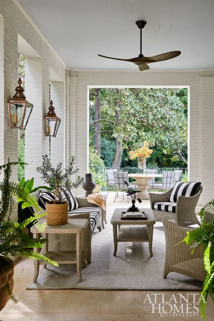 Covered porch with wicker furniture, black and white striped cushions, and view of garden