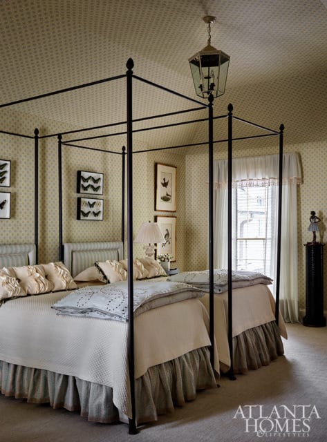 Bedroom with two four-poster beds, patterned wallpaper, and a hexagonal lantern chandelier.