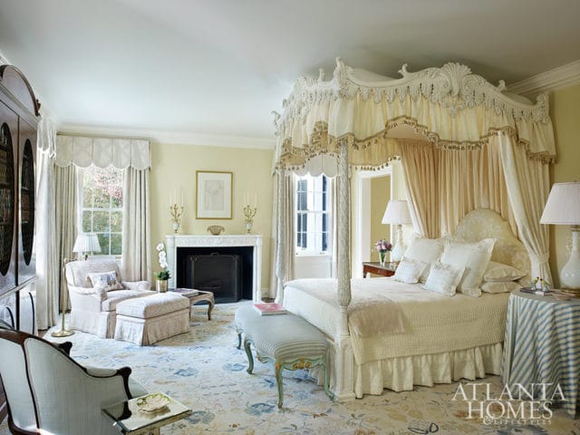 Bedroom with a four-poster bed, fireplace, and sitting area. Yellow walls and floral rug.