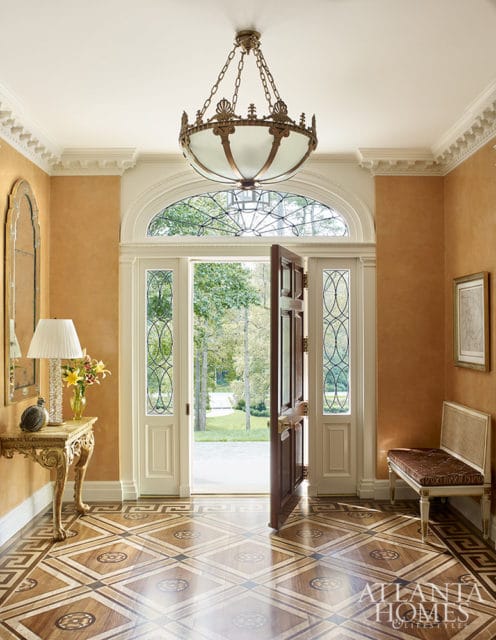 Entryway with ornate wood floor, arched transom window, and open front door.